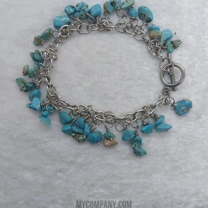 Silver stainless steel charm bracelet with numerous turquoise gemstone chips and a toggle clasp.