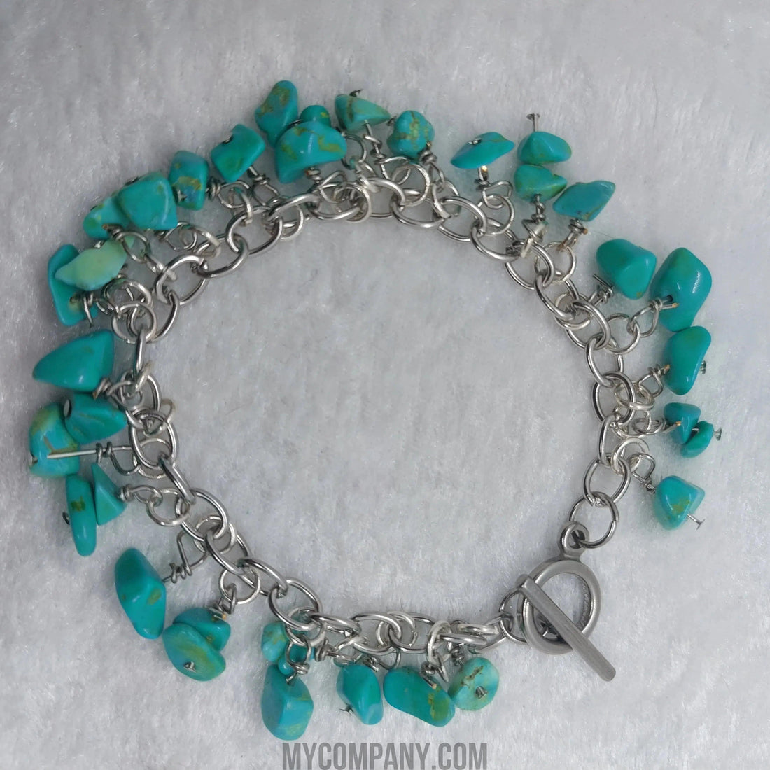Silver stainless steel charm bracelet with numerous turquoise howlite gemstone chips.