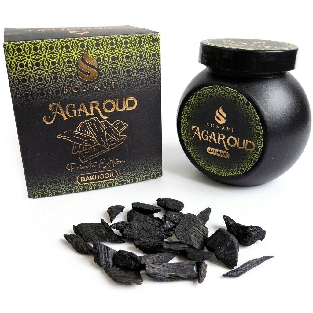Black jar of Sonavi Agar Oud bakhoor incense chips next to its decorative box, with small dark agarwood chips scattered about — 40g natural agarwood resin blend.