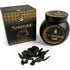 Black jar of Sonavi Amber Oud bakhoor incense chips with decorative gold lid, next to its matching box, with small oud wood pieces scattered on the surface — 40g warm amber and oud resin blend for ritual and meditation.