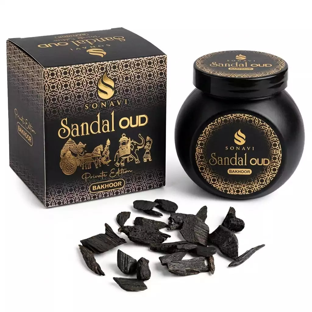 Black jar of Sonavi Sandal Oud bakhoor incense chips with gold label, next to its decorative box with intricate designs, and small oud wood pieces scattered in front — 40g natural sandalwood and agarwood grounding blend.
