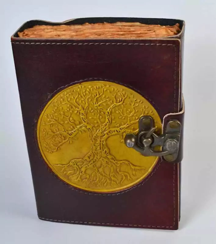 Leather-bound journal with golden embossed Tree of Life design on cover with aged paper and metal latch closure