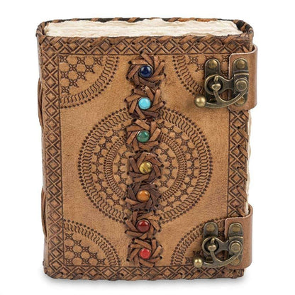 Handcrafted leather journal with intricate embossed patterns and colorful gemstones along the spine — secured with decorative brass clasps.