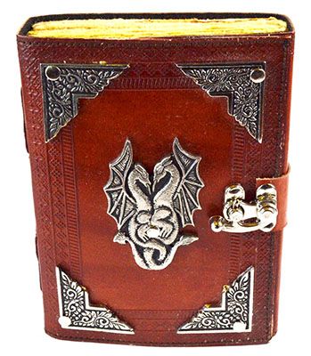 A leather-bound book with ornate silver corners and a dragon emblem on the cover, secured with a clasp. The pages are edged in yellow, giving it a vintage appearance.
