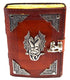 A leather-bound book with ornate silver corners and a dragon emblem on the cover, secured with a clasp. The pages are edged in yellow, giving it a vintage appearance.