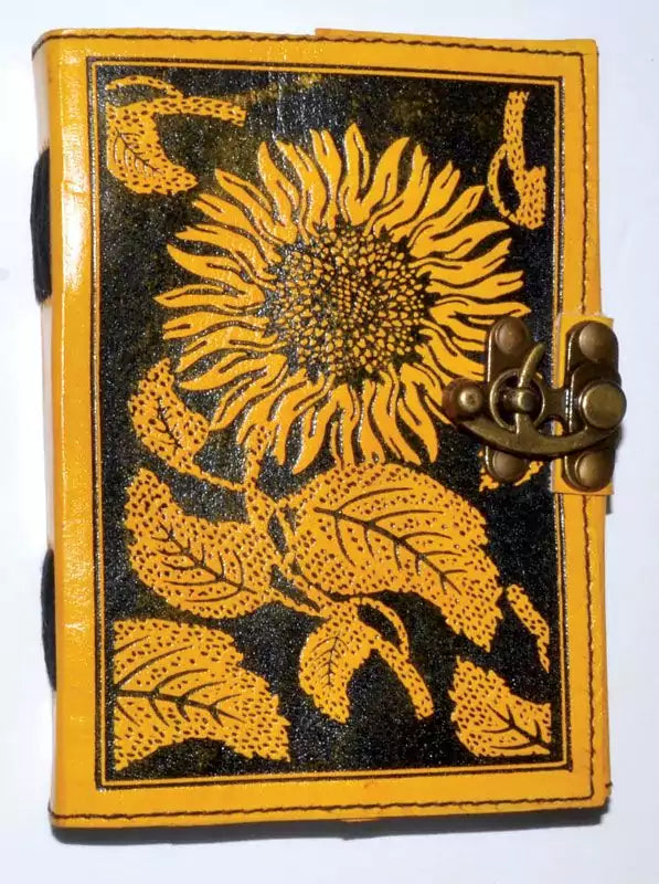 Leather-bound blank journal with embossed sunflower design on the cover and a decorative latch closure, suitable for use as a grimoire or spell journal.