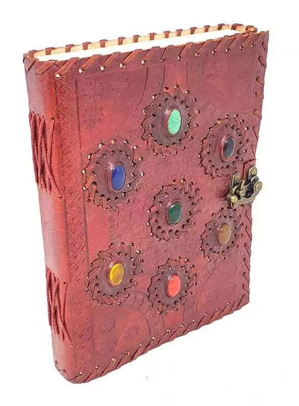 6x8 inch handcrafted embossed leather journal with seven real gemstone chakra stones embedded in the cover and a metal latch — for chakra practice and spiritual writing.