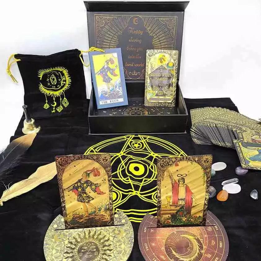 Rider-Waite black and gold foil tarot cards displayed on black cloth with crystals, a feather, and a decorative box showing mystical tarot imagery.
