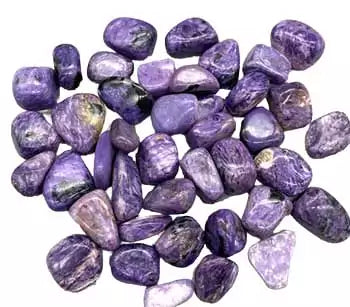 A pile of polished charoite tumbled stones in rich swirling violet and lavender patterns, the rare Siberian crystal, sold in 1 lb bulk lots.