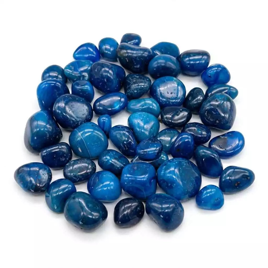 Blue onyx tumbled stones in a pile showing smooth polished surfaces with deep teal coloring — heat-treated chalcedony bulk crystals.