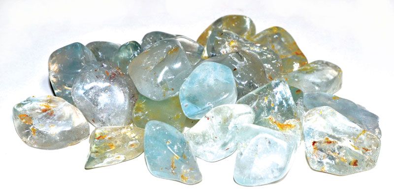 A collection of polished blue topaz tumbled stones in sky-blue and pale azure tones, sold in 1 lb bulk for throat chakra and stress-relief crystal work.