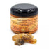 2oz jar of palo santo granular resin incense with loose resin pieces scattered beside it, for use on charcoal discs in ritual burning.