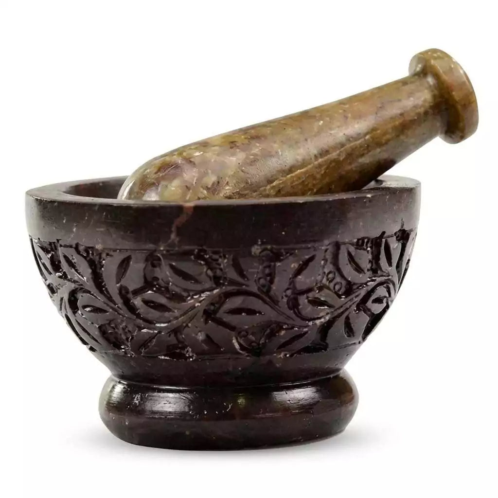 Hand-carved soapstone mortar and pestle set with intricate leaf and vine relief design around the exterior, used for grinding herbs and resins.