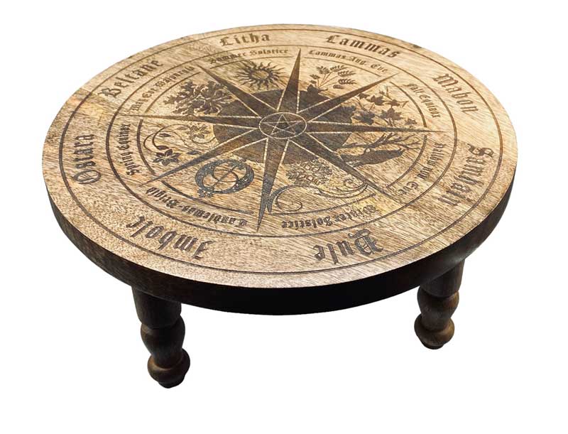 Round carved wooden altar table with a wheel-of-the-year compass design, sabbat symbols, and directional markings carved into the surface — 11¾-inch diameter.