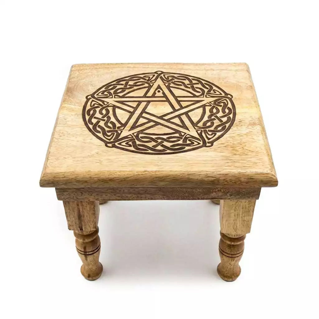 Carved wooden pentagram altar table with intricately cut five-pointed star design and raised leg platform for ritual display