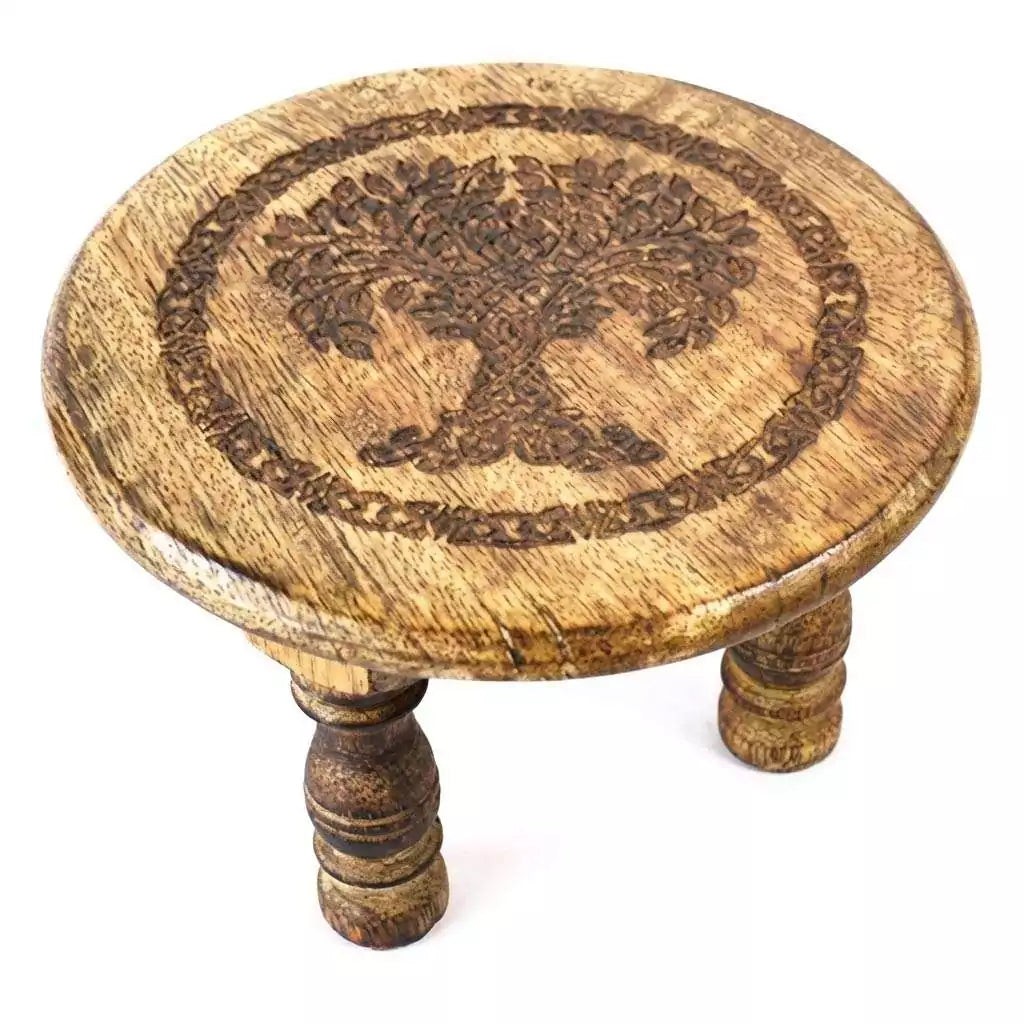 6-inch round wooden altar table with a carved Tree of Life design on the surface and three sturdy wooden legs supporting it.