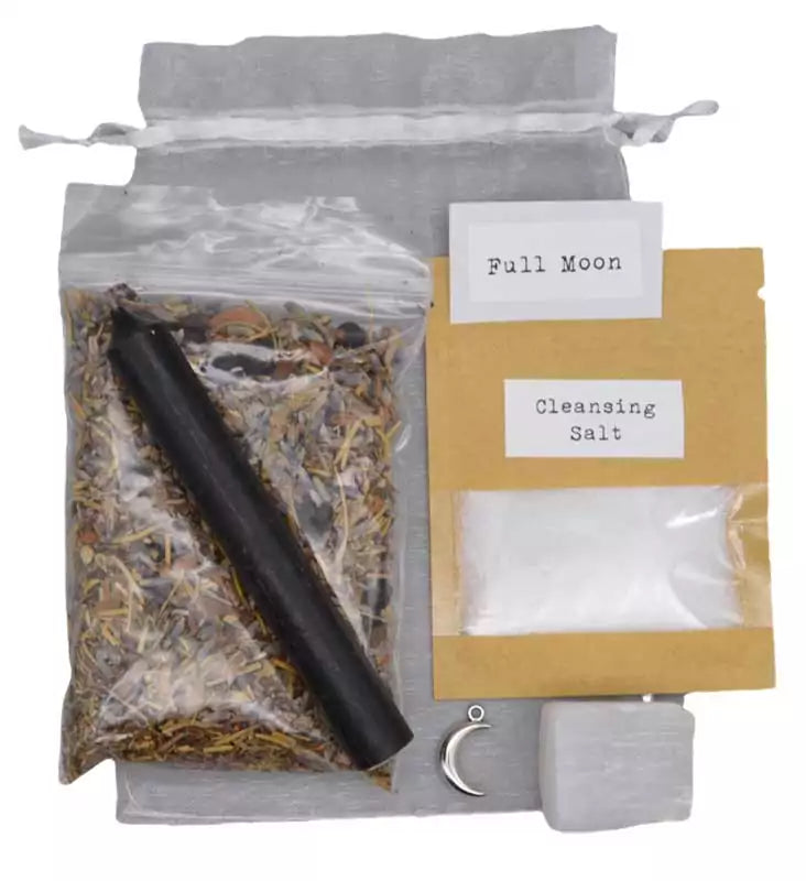 Full Moon Ritual Kit contents displayed — bag of herbs, black candle, cleansing salt packet, and small herb pouch on light gray background for lunar cleansing ritual.