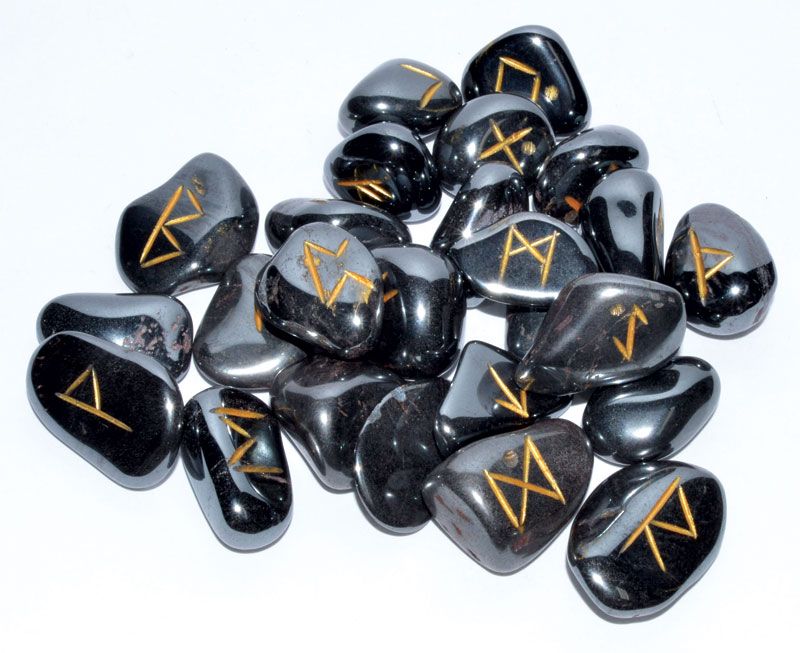 Hematite rune set showing 25 carved Elder Futhark rune stones in polished dark silver hematite displayed with rune symbols facing up.