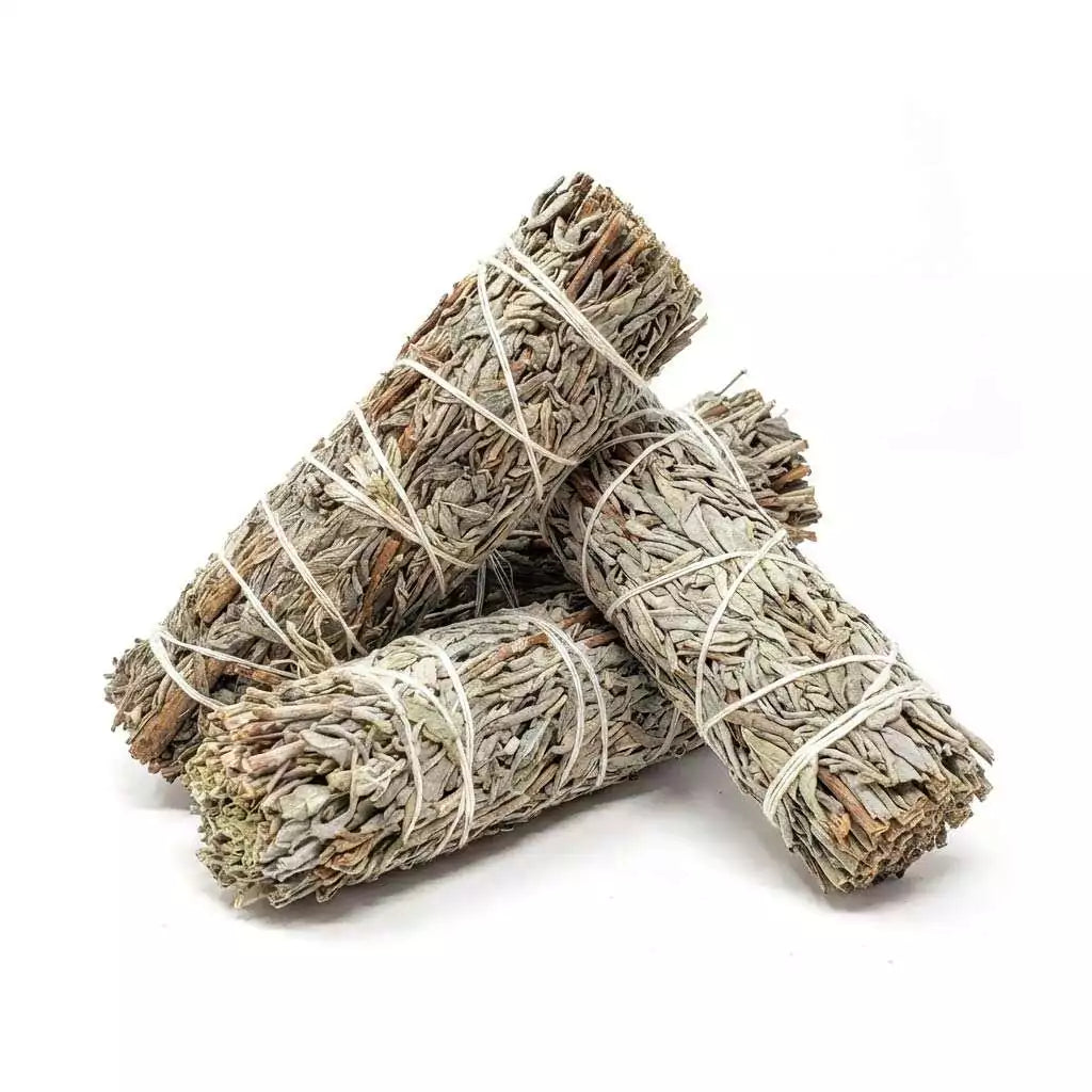 Multiple bundles of dried blue sage smudge sticks tied with string arranged together — hand-rolled artisan herb bundles for peaceful clearing and meditation rituals.