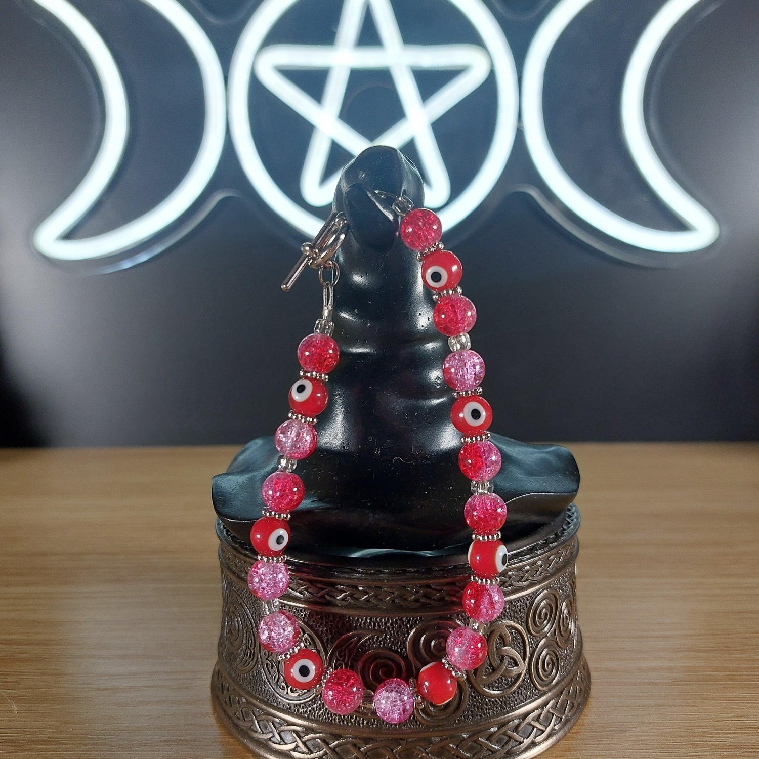Pink and red glass bead bracelet with evil eye charms and a toggle clasp.