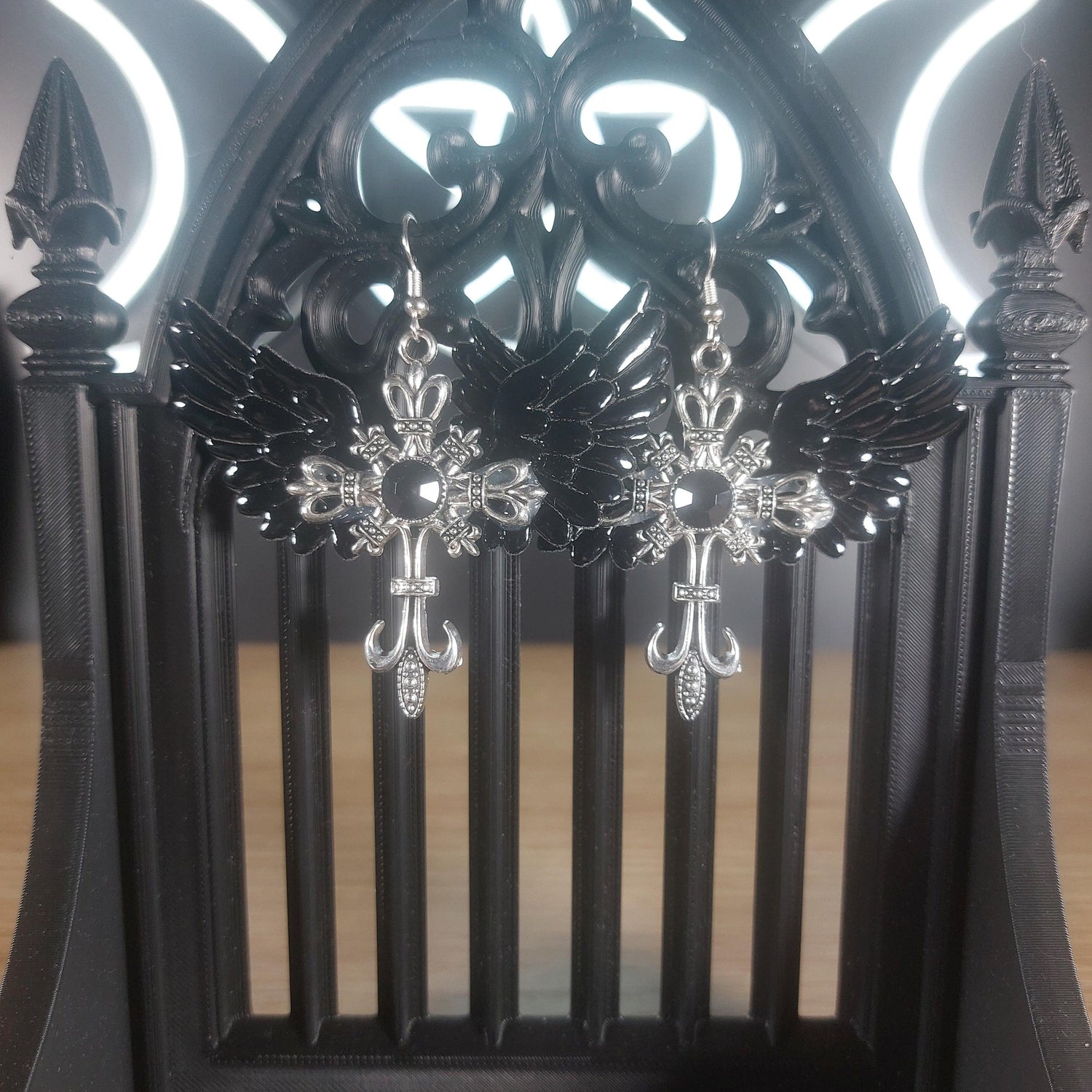 Black winged silver-tone cross dangle earrings with intricate gothic details.