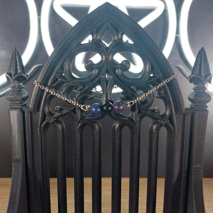 Sagittarius power stone bracelet with blue lapis lazuli, purple amethyst, and black obsidian beads on a gothic stand.