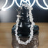 Clear quartz crystal chip bracelet with stainless steel toggles on a black display stand.