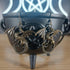 Pair of large bronze dragon dangle earrings with detailed wings and coiled bodies, hanging from a black cauldron.