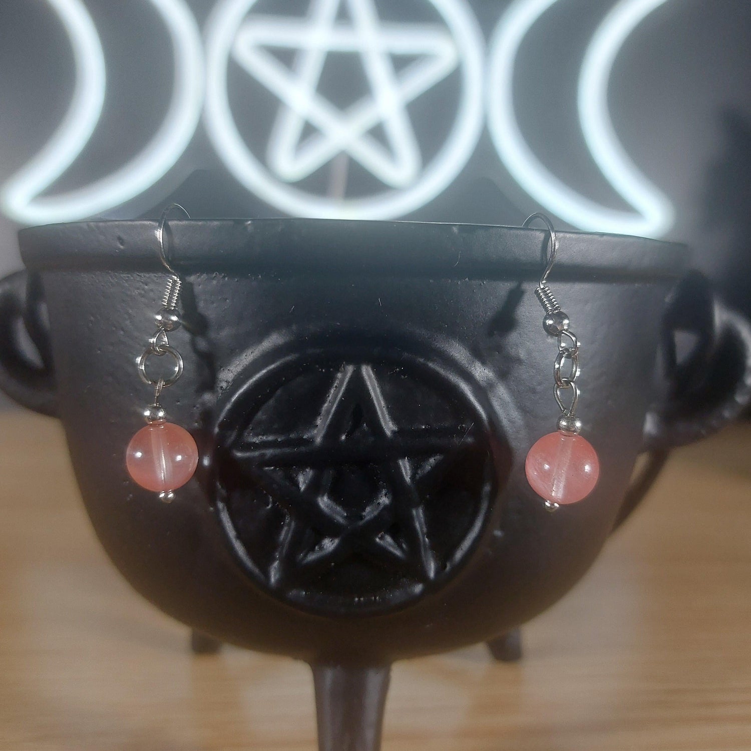 Pink rose quartz crystal beaded dangle earrings on a black cauldron with a Triple Moon pentacle symbol.