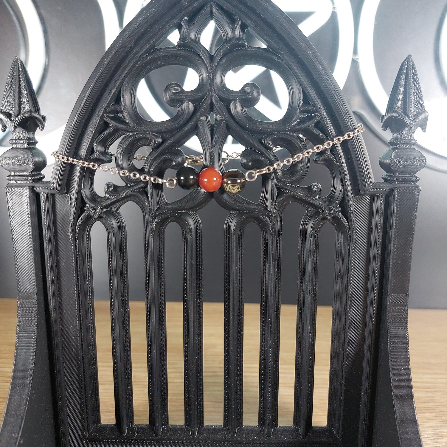 Silver chain bracelet with red carnelian, black obsidian, and smokey quartz beads on a gothic black stand.