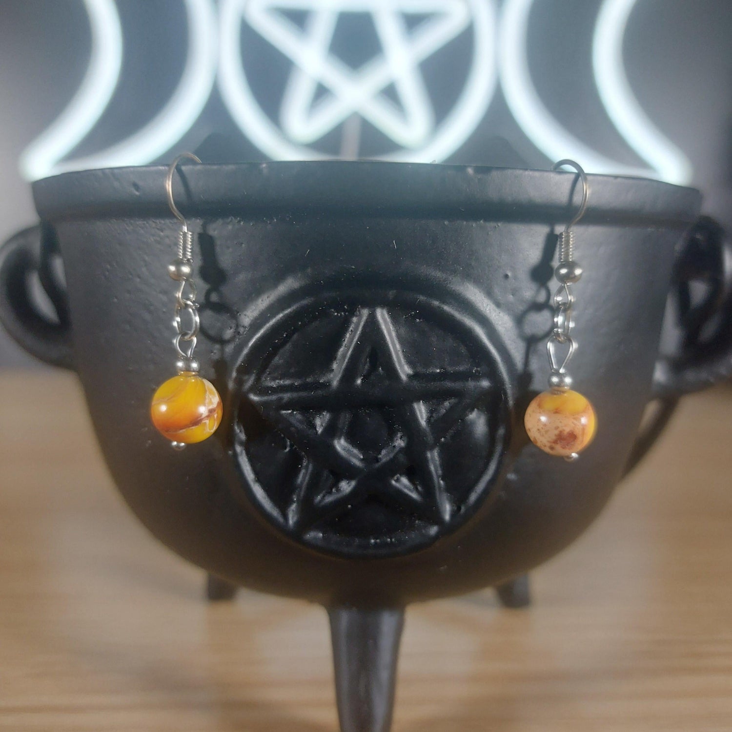 Yellow mookaite crystal beaded dangle earrings with silver hooks, displayed in a black cauldron.