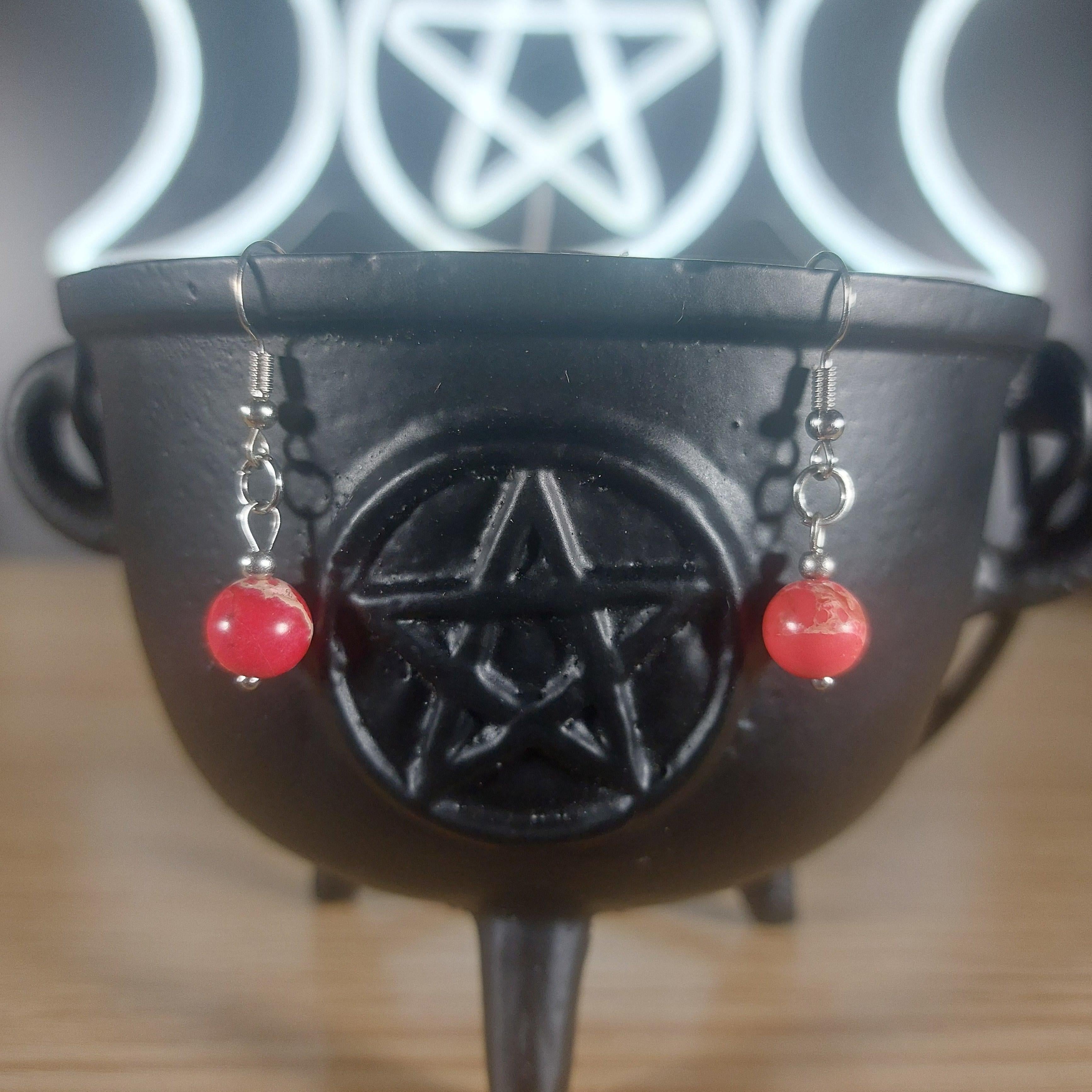 Red jasper crystal beaded dangle earrings with silver hooks, displayed on a black cauldron.