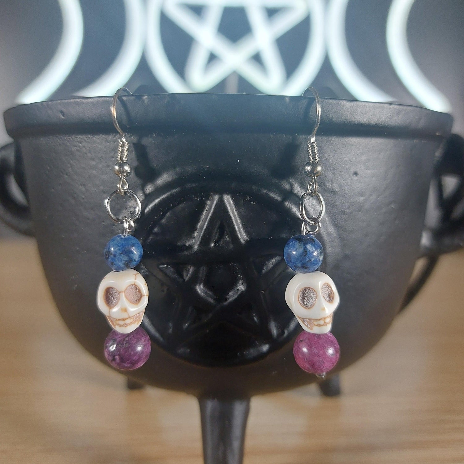 White howlite crystal skull dangle earrings with blue and purple glass beads.