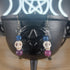 White howlite crystal skull dangle earrings with blue and purple glass beads.