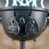 Silver tone evil eye quija planchette dangle earrings hanging from a black cauldron.