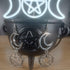 Silver moon and pentagram dangle earrings on a black cauldron, with a glowing triple moon symbol in the background.