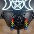 Rainbow plastic bicone dangle earrings on a black cauldron with a glowing triple moon and pentagram symbol.