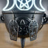Silver-tone coffin dangle earrings with intricate spider web and spider cutouts, displayed on a black cauldron.