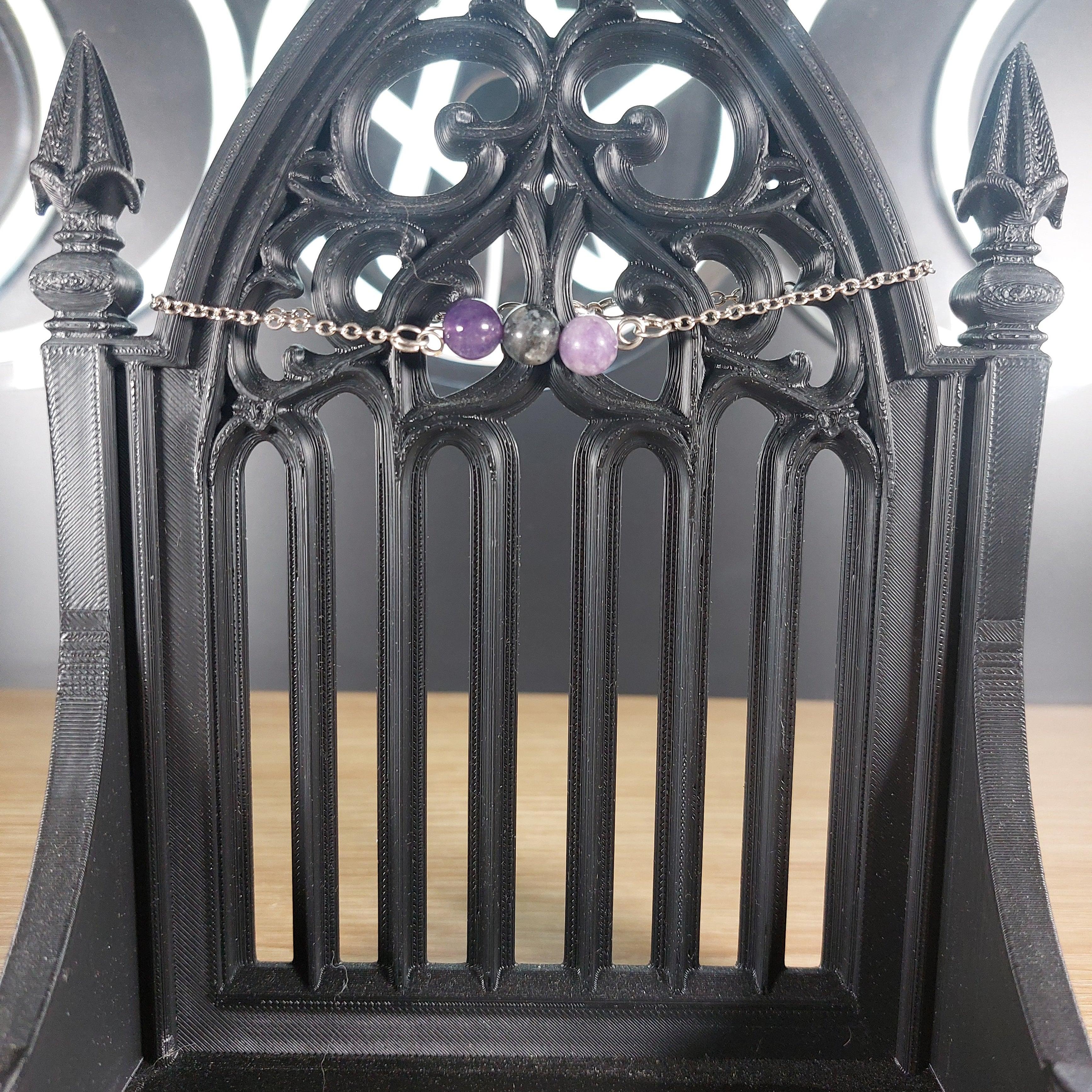 Silver tone chain bracelet with labradorite, amethyst, and lepidolite beads on a gothic black stand.