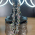 Silver chain dangle earrings with iridescent, multicolored hematite beads on a dark witch hat display.