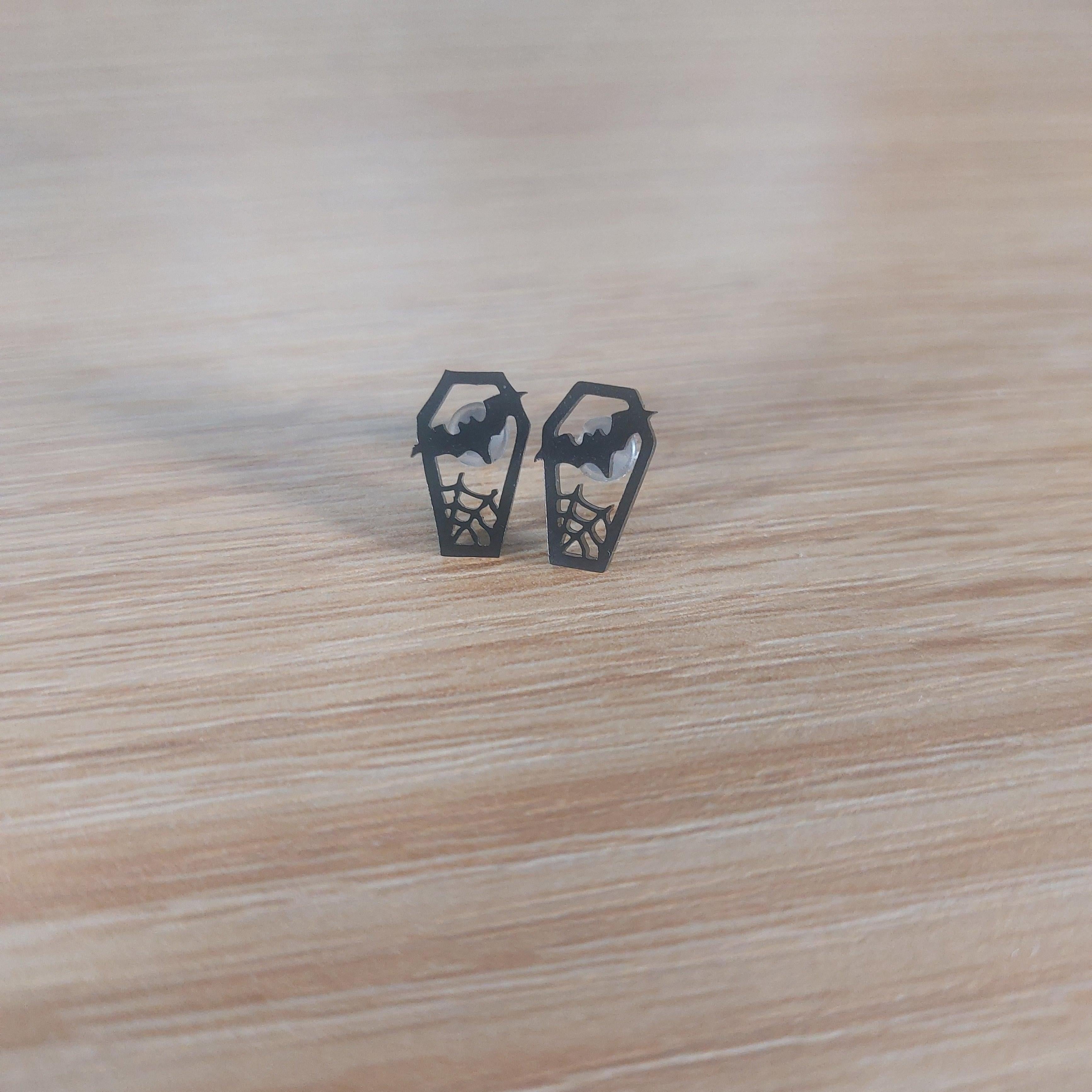 Pair of black coffin stud earrings with bat and spiderweb cutouts.