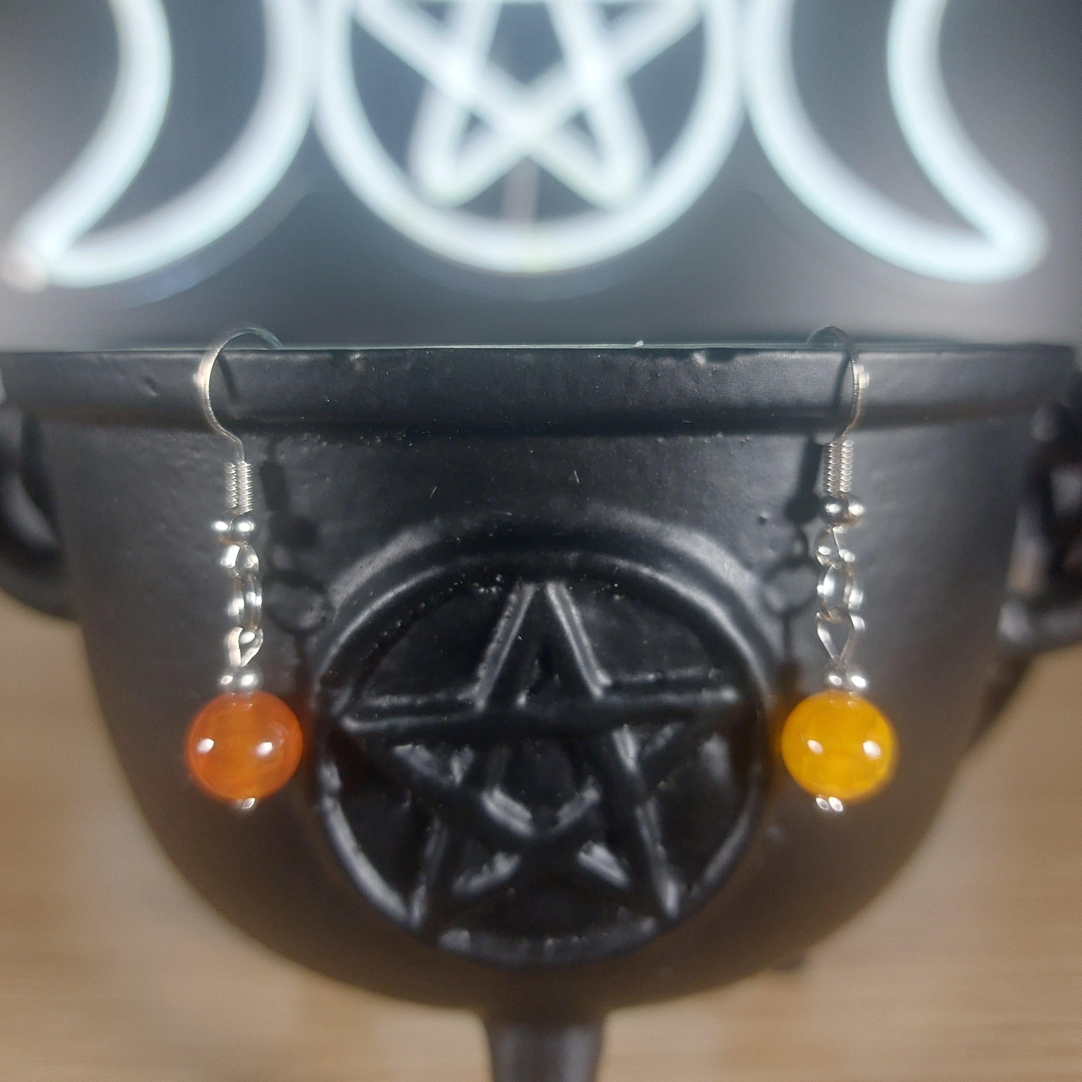 Yellow chalcedony crystal beaded dangle earrings with silver hooks, displayed on a black cauldron.