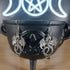 Antique silver tone dragon dangle earrings hanging from a black cauldron.
