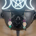 White howlite skull earrings with purple and green glass beads dangling from silver hooks.