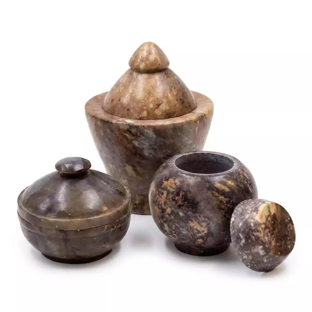 Set of four carved soapstone Gini jars in various sizes with intricate patterned designs and earthy tones — stone altar storage containers for herbs, resins, and ritual supplies.